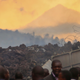 Residents check the damages caused by lava from the overnight eruption of Mount Nyiragongo, seen in the background, in Buhene, on the outskirts of Goma, Congo in the early hours of Sunday, May 23, 2021.